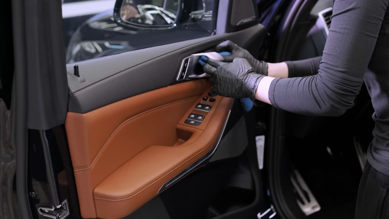 el lavador de coches profesional con guantes negros limpia el coche después de lavar y forrar la cerámica. conceptos de: trabajo profesional, varias herramientas de lavado, limpieza para brillar.