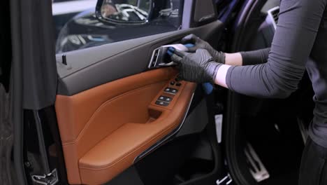 professional car washer in black gloves wipes the car after washing and lining ceramics. concepts of: professional work, various washing tools, cleaning to shine.