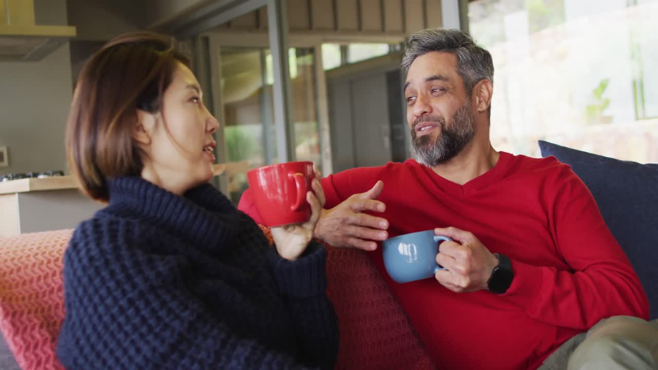 다양한 행복 한 커플 이 거실 에 앉아 커피 를 마시고 대화 하고 있다