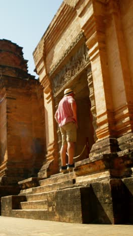 male tourist in pink shirt visits iconic temples around angor wat - vertical of old adventure traveller