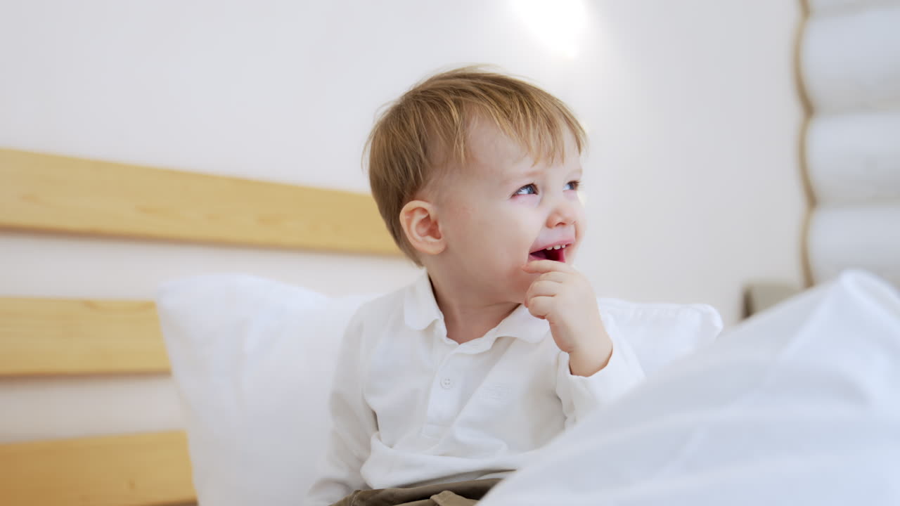 Adorable blond toddler drinks from bottle. Kid spills water and coughs. Close up.