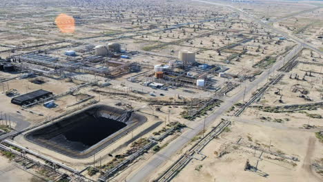 aerial view flying over vast missouri triangle oil fields refinery stations on california desert landscape