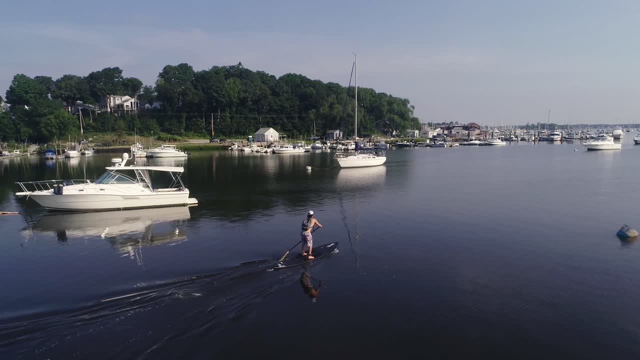 Padleboarder padler afsted i en havn.