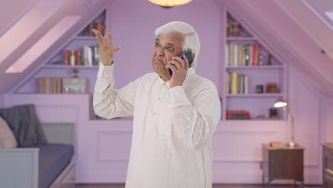 un anciano indio enojado gritando en el teléfono.