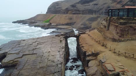 drone video of a crevasse on a rocky outcrop on the beach shore