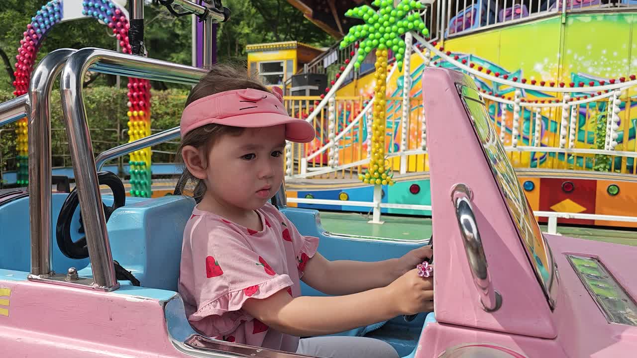 retrato de una niña caucásica girando la rueda de un coche de juguete en el parque de atracciones de seúl land