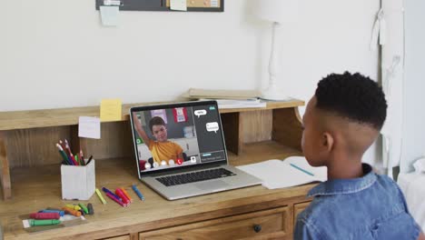 Niño-Afroamericano-Levantando-Las-Manos-Mientras-Realiza-Una-Videoconferencia-En-Una-Computadora-Portátil-En-Casa