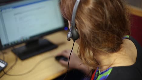 girl typing on the keyboard, other hand is on the mouse, watching on the monitor, put the heandphones