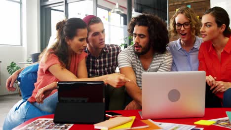 Business-executives-discussing-over-laptop-in-meeting