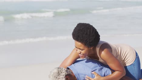 feliz pareja afroamericana caminando y abrazándose en una playa soleada