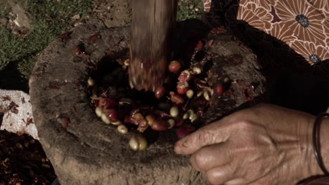 old woman's hands crushing nuts with traditional wooden mortar and pestle