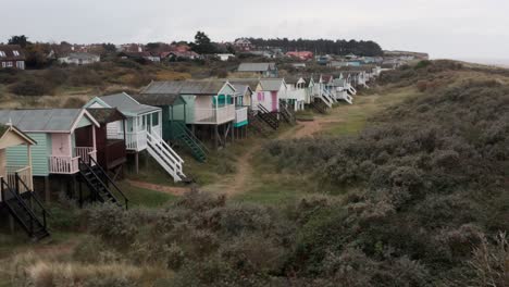 dolly adelante disparo de drones hacia coloridas cabañas de playa junto al mar inglés