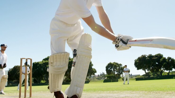 Battitore che esegue un colpo difensivo durante una partita di cricket