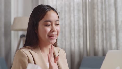 close up of sick asian businesswoman holding a thermometer to the video call with doctor on a laptop while working at home