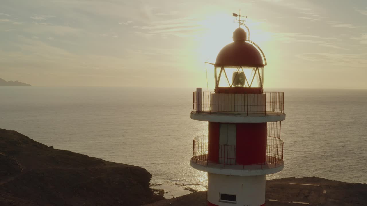 tiro de drone de un faro con sol y océano en el fondo