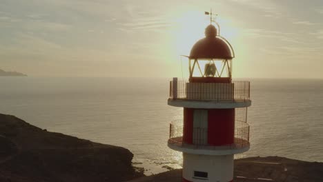 Drohnenaufnahme-Eines-Leuchtturms-Mit-Sonne-Und-Meer-Im-Hintergrund