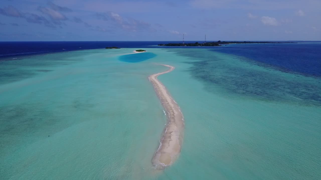 Long sandy dune surrounded by shallow turquoise lagoon with clear water in the middle of Maldivian archipelago, deep blue ocean horizon under purple sky