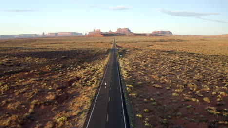 drone footage of man skateboarding in monument valley along forest gump highway in utah