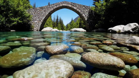 crystal clear river with stone arch bridge