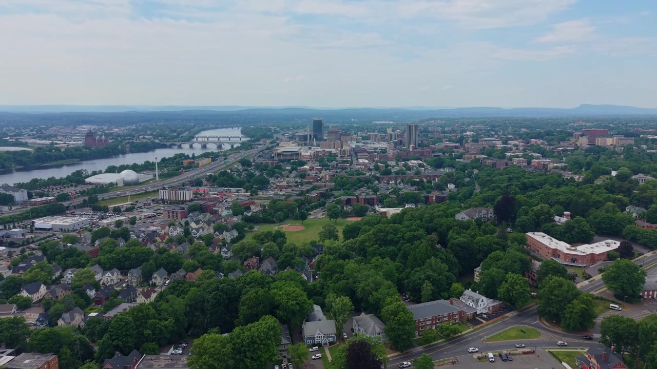 Springfieldin kaupunki ja Connecticut-joki maiseman poikki rakennusten ja puiden kera Massachusettsissa. Ilmakuva, jossa kamera vetäytyy taaksepäin ja nousee ylöspäin.