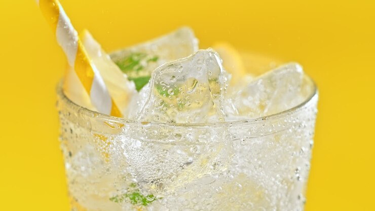 Glass Of A Summer Sparkling Drink With A Straw, Ice Cubes, Mint And Lemon Slices - Crane Shot