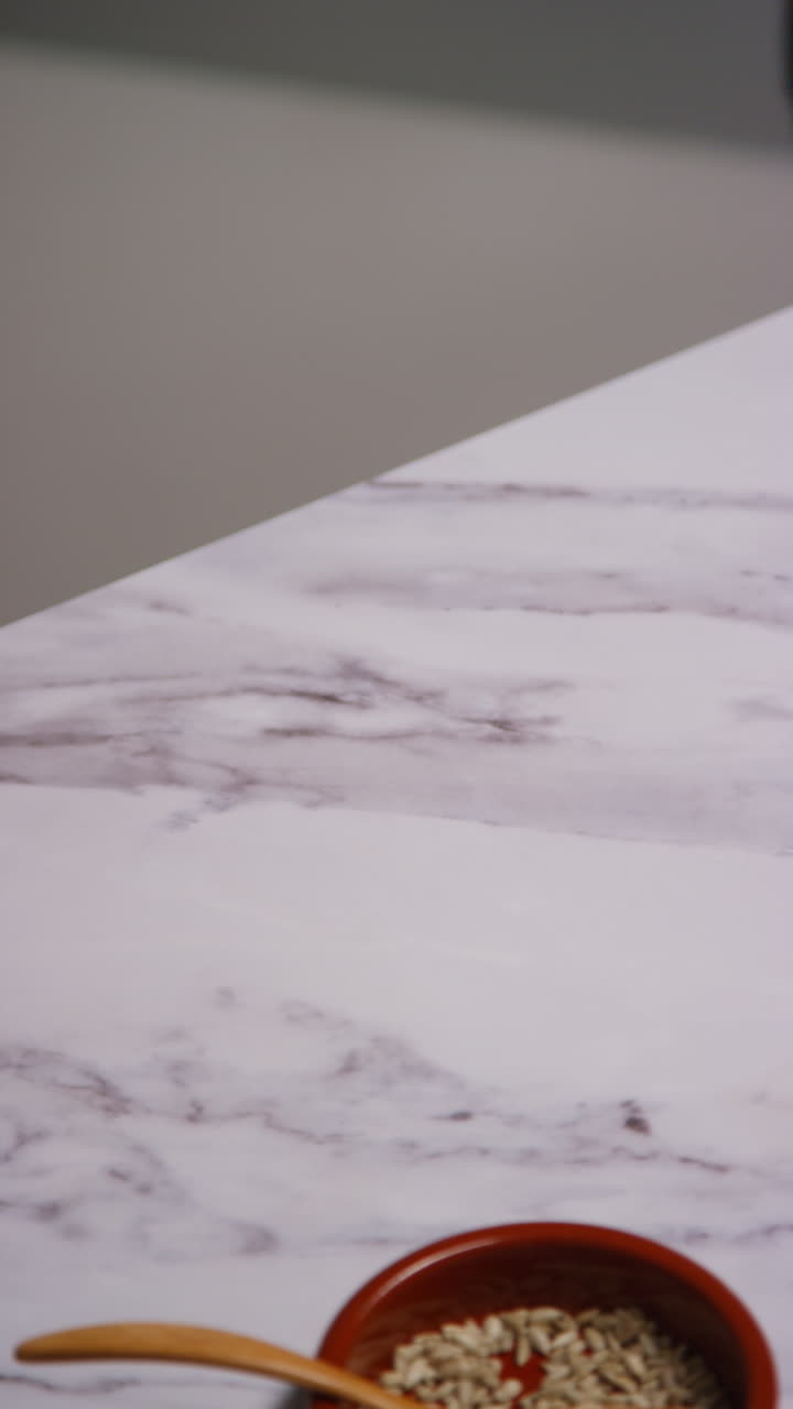 video vertical de cerca de una mujer en casa en la cocina preparando una comida saludable vegetariana o vegana comiendo un plato de hojas de ensalada con semillas y aderezo