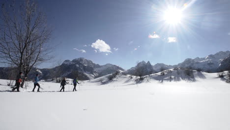 一群徒步旅行者在晴朗的阳光天在山上穿过雪地