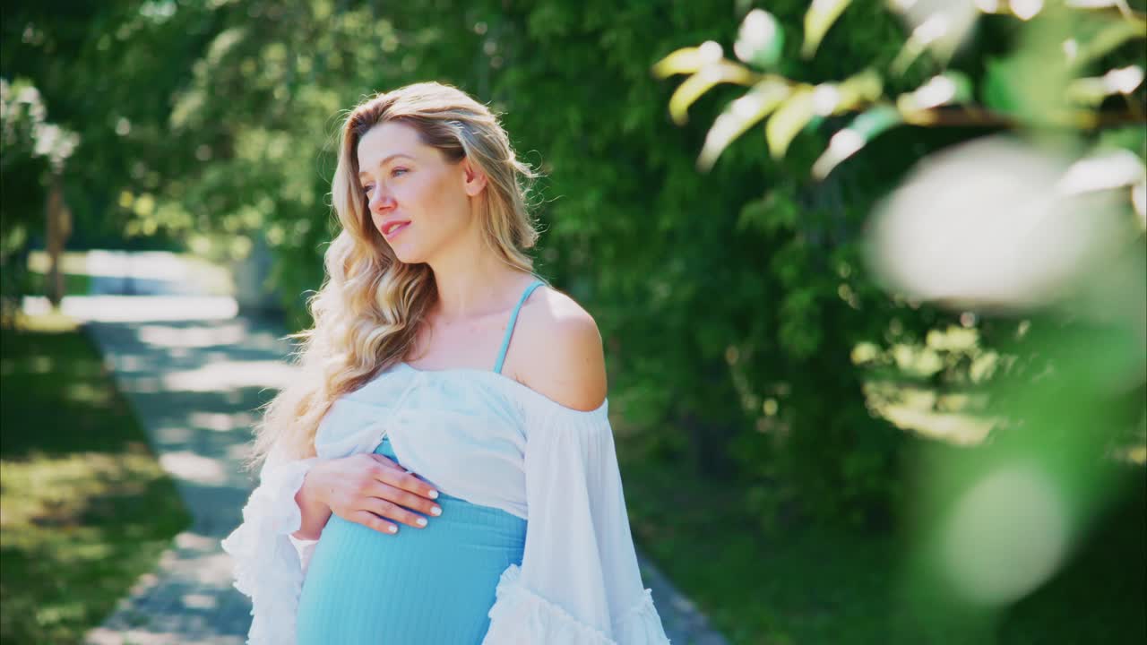 Serene Pregnant Woman Gently Touching Her Belly in a Sunny Park