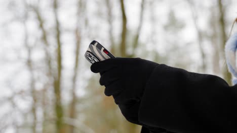 young woman in gloves in the park uses the phone