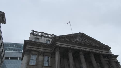 english flag flying over mansion house london on a cloudy day from below