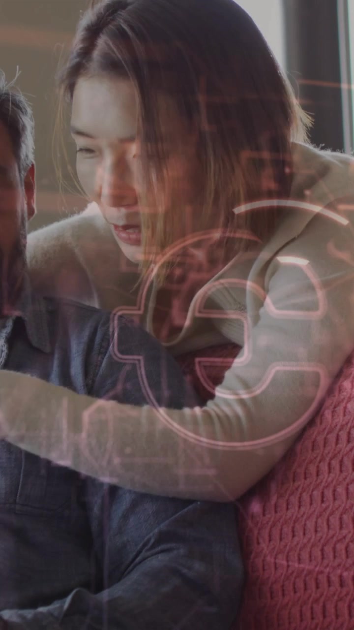 Vertical video: Woman leaning over man on sofa, pointing at screen, causing neon overlay for tech