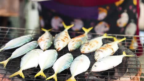 fresh mackerel being grilled at a market stall