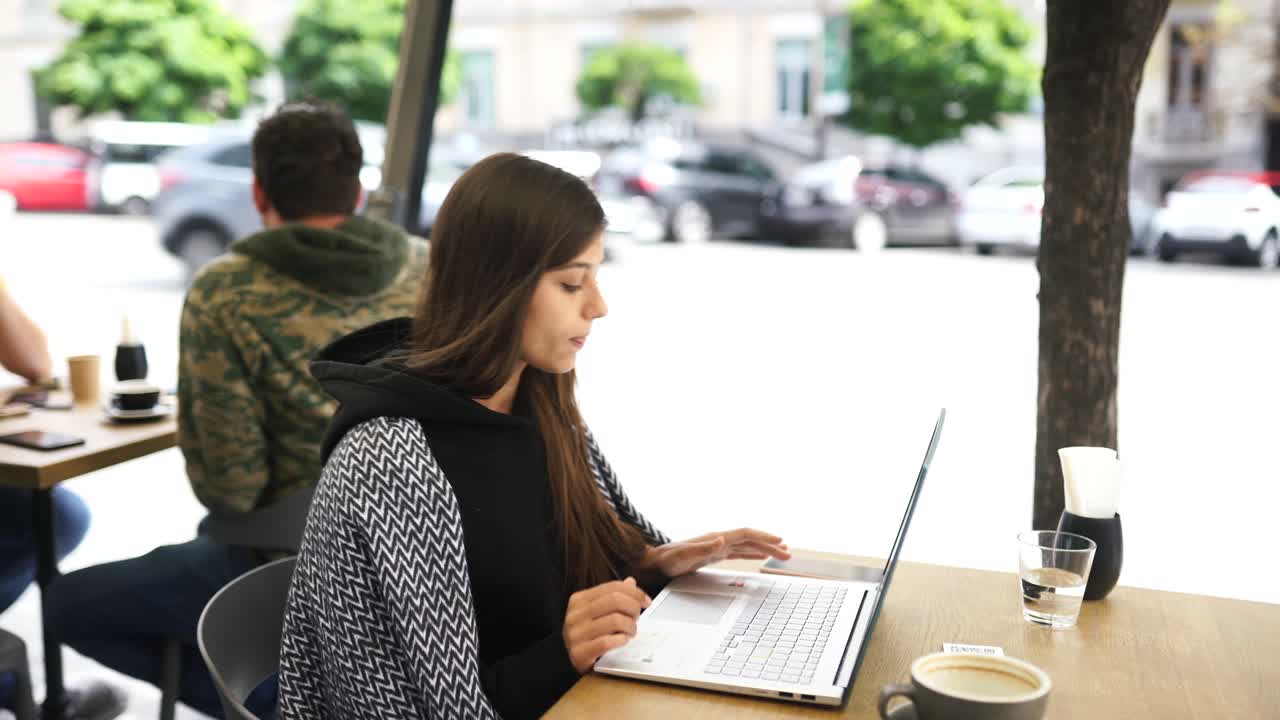 mujer joven trabajando en una computadora portátil en un café