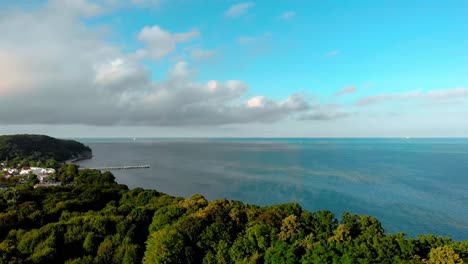 Hermoso-Mar-Azul,-Nubes-Sobre-El-Mar-Azul,-Vuelo-Lento-Sobre-Los-árboles-Con-Vista-A-La-Bahía,-Tiro-Aéreo-Suave