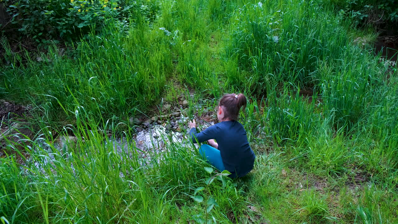 자연에서 칼을 가지고 노는 어린 소녀, 풀을 숲의 작은 개울로 자르고, 야외 생존 칼, 아이가 사용하는 도구