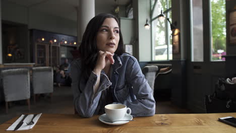 Beautiful-Hispanic-latina-brunette-sitting-at-the-table-waiting-while-having-a-coffee