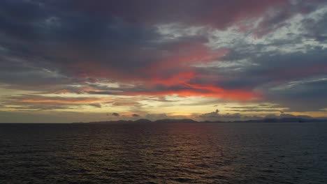 flying over water towards mountains during  beautiful sunset