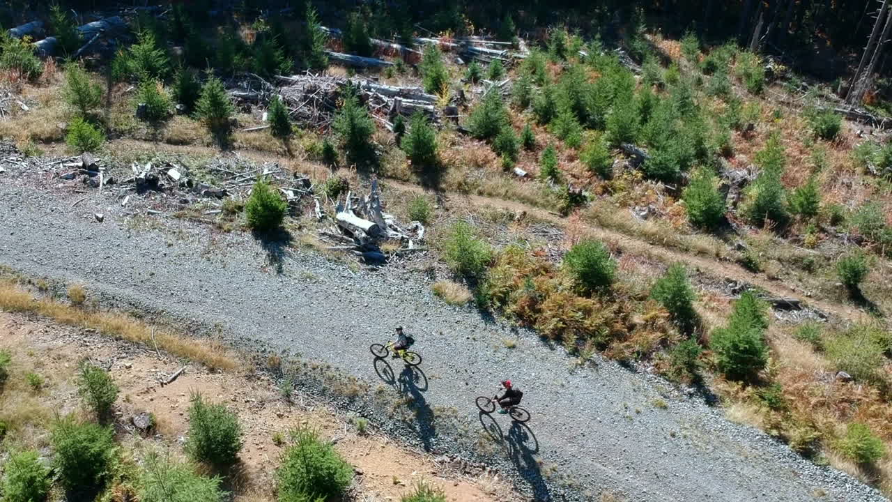 imágenes de drones de 2 personas en bicicletas de montaña recorriendo la carretera en un hermoso día de verano en el noroeste del pacífico