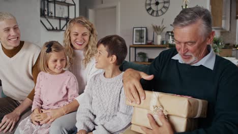 Senior-caucasian-grandfather-sharing-the-Christmas-gifts-with-family.