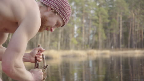 cámara lenta - bañista de hielo en topless rompiendo el hielo con un palo para hacer un agujero