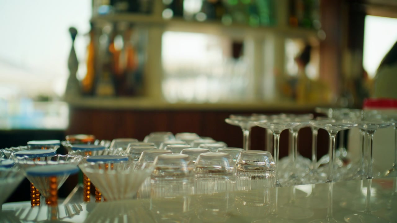 Close-up of empty wine and cocktail glasses on a bar counter with bottles behind, Cannes, France