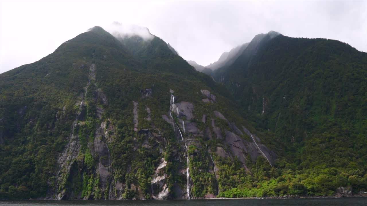 Milford Sound Fiord Lady Bowen Stirling Park Narodowy Fiordland Nowa Zelandia Aotearoa rejs łodzią Basen Słodkowodny Wiosenny poranny deszcz Region Southland Góra Słoń Lew krajobraz naturalny.