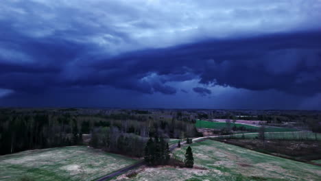 dark storm clouds roll in over the quiet countryside, illuminated by flashes of distant lightning - aerial drone shot