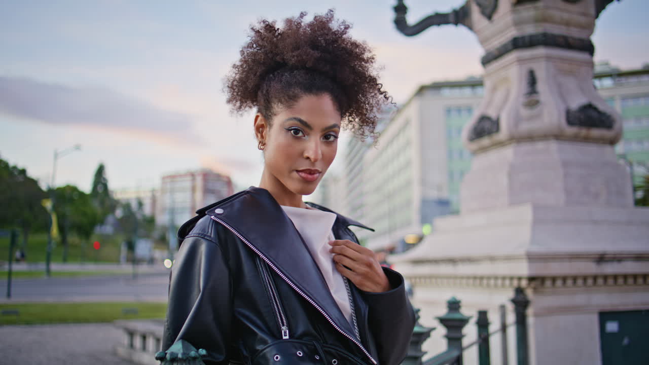 Trendy model standing city square in jacket closeup. Confident woman