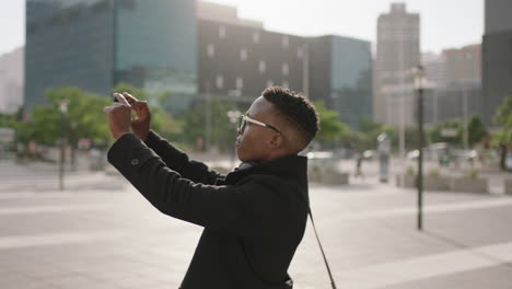 retrato de un estudiante afroamericano de moda tomando fotos de la ciudad urbana usando tecnología de video de teléfono inteligente disfrutando de viajes turísticos