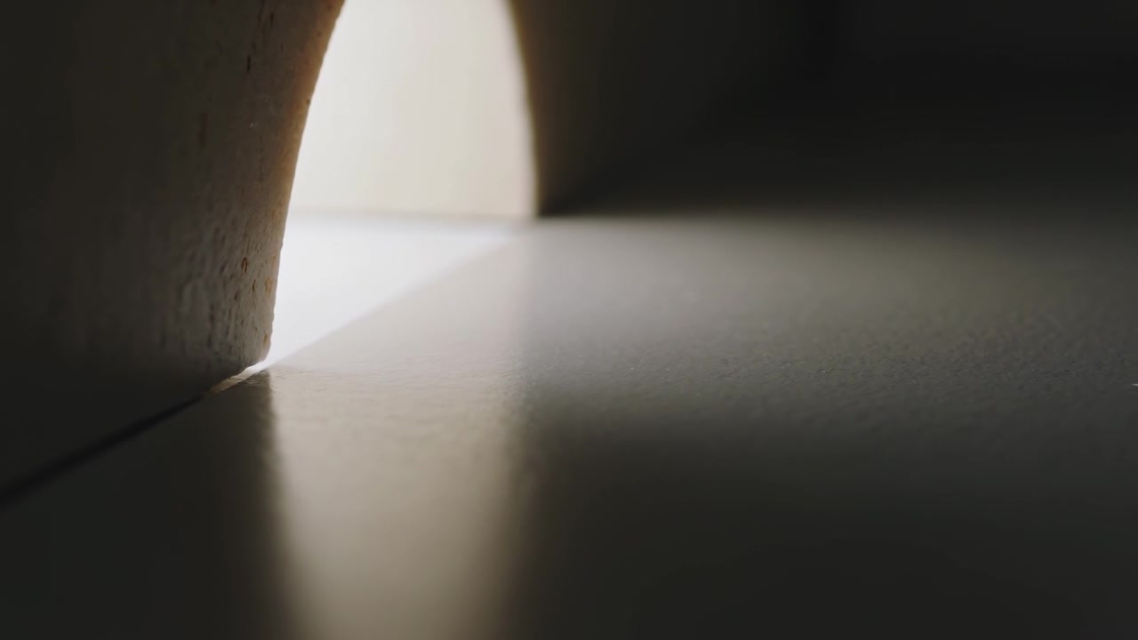 カメラがスタジオをパンすると、平面にアーチの反射が映り、継ぎ目と三角形の光線が見える。コピー空間あり。