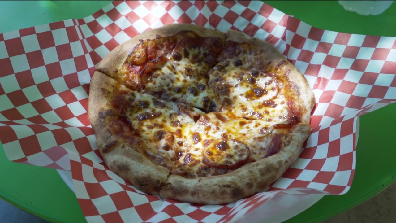 Pizza Personale Unta al Salame Piccante Consumata all'Aperto su Tavolo Verde