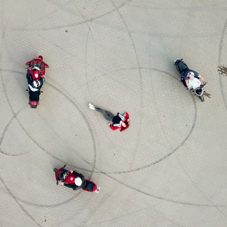 close-up of a sexy woman with red hair and jeans lying on the road and three motorbikers riding around her. aerial view