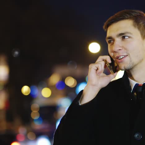 A-young-man-walks-through-the-night-city-and-uses-a-smartphone-4