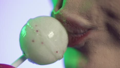 mujer lamendo helado de cereza con seducción, boca en primer plano sobre fondo verde